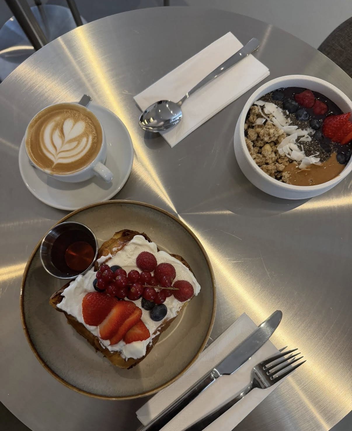 Latte art, açaí bowl and french toast on a stainless steel table at People of Coffee